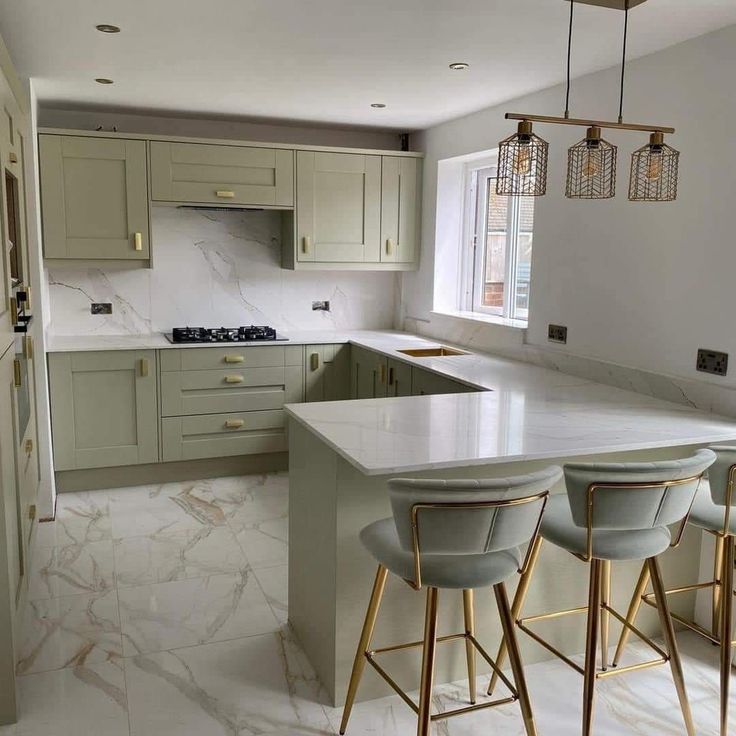 a kitchen with marble counter tops and gold bar stools in front of the island