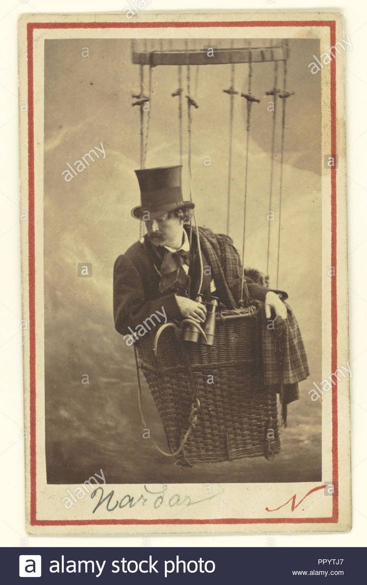 an old time photo of a man in a top hat and coat on a hot air balloon