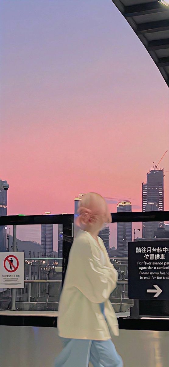 a person walking down a walkway in front of a cityscape at sunset or dawn