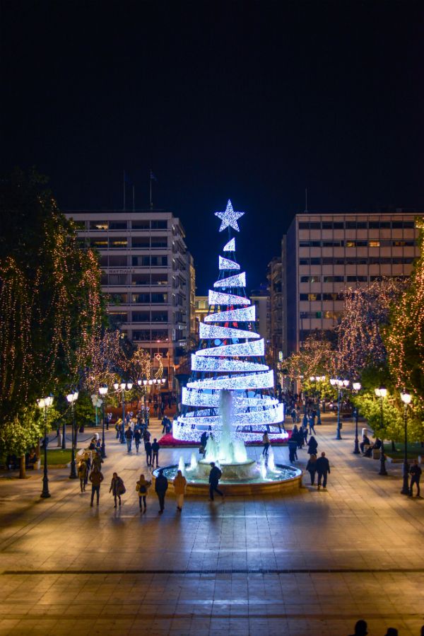 a lit christmas tree in the middle of a plaza