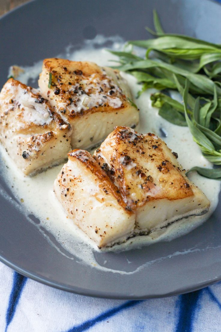 three pieces of fish sitting on top of a blue plate next to some green beans