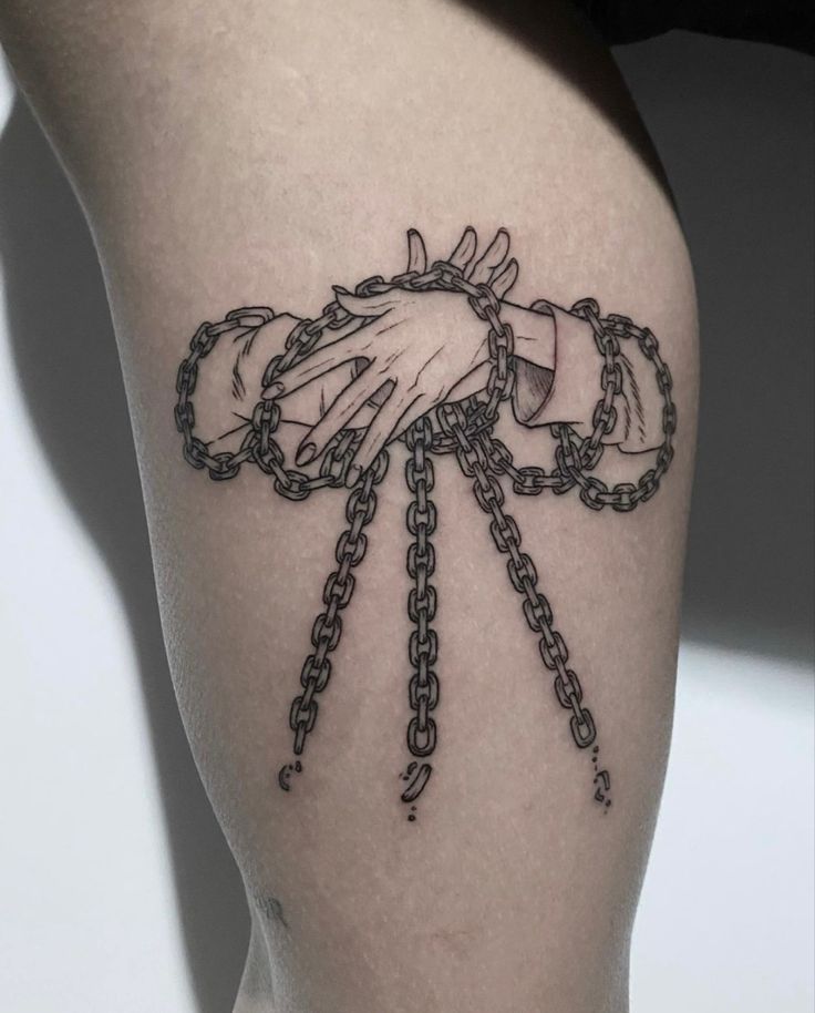 a tattoo on the thigh of a woman with chains around her ankles and hands holding each other