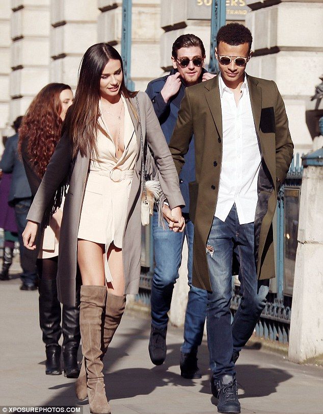 the man and woman are walking down the street together, holding hands with each other