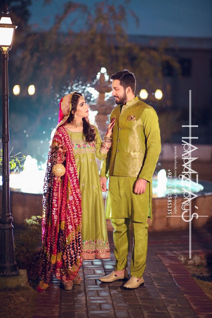 a man and woman standing next to each other in front of a street light at night