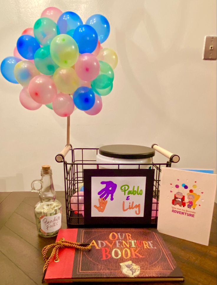 a table topped with books and balloons on top of a wooden table next to a bottle