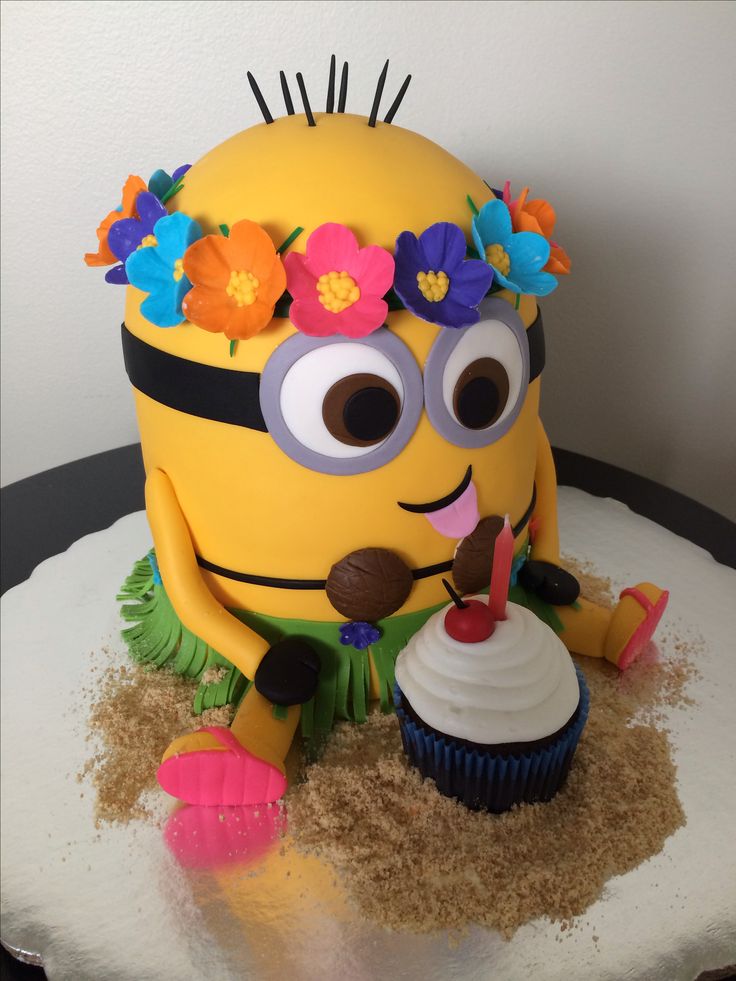 a birthday cake made to look like a minion with flowers in her hair and holding a cupcake