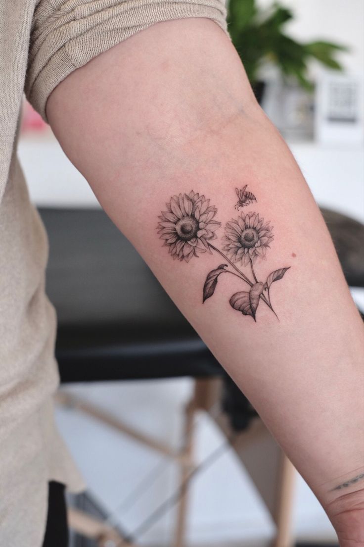 a woman with a tattoo on her arm holding onto a flower in the other hand