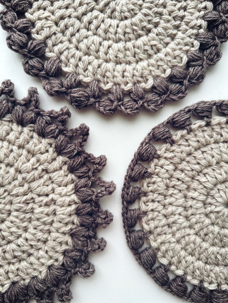 three crocheted doily are shown on a white surface, one is brown and the other is gray