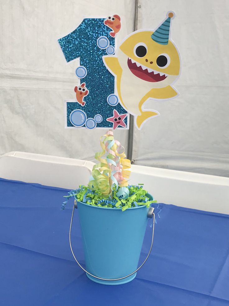 a birthday centerpiece with a shark and number one on it in a blue bucket