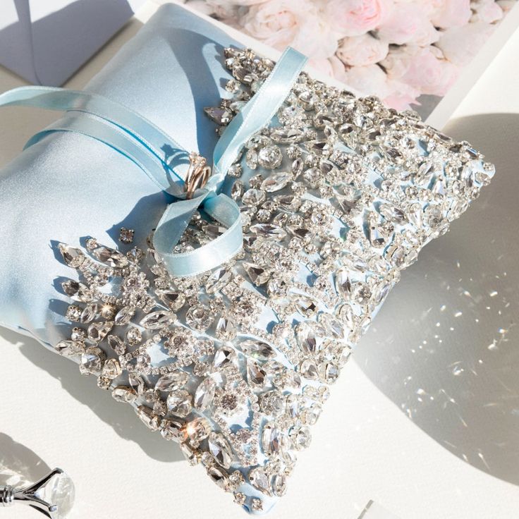 a blue ring pillow sitting on top of a table next to a vase with flowers