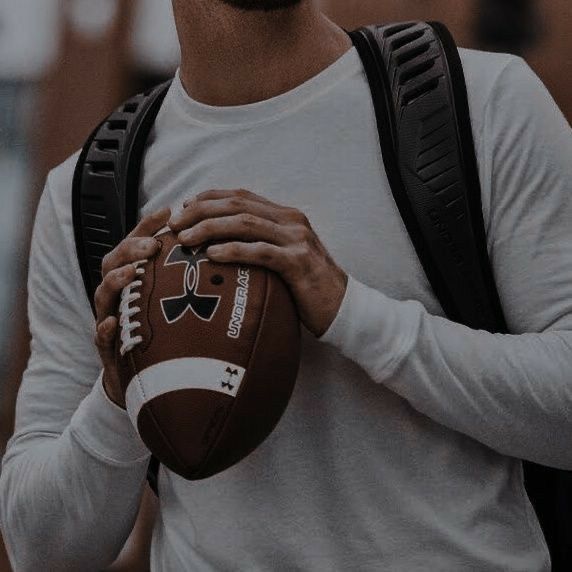 a man holding a football in his right hand and wearing a backpack on his left