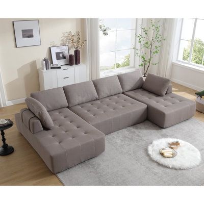 a grey sectional sofa sitting on top of a rug in a living room next to a window