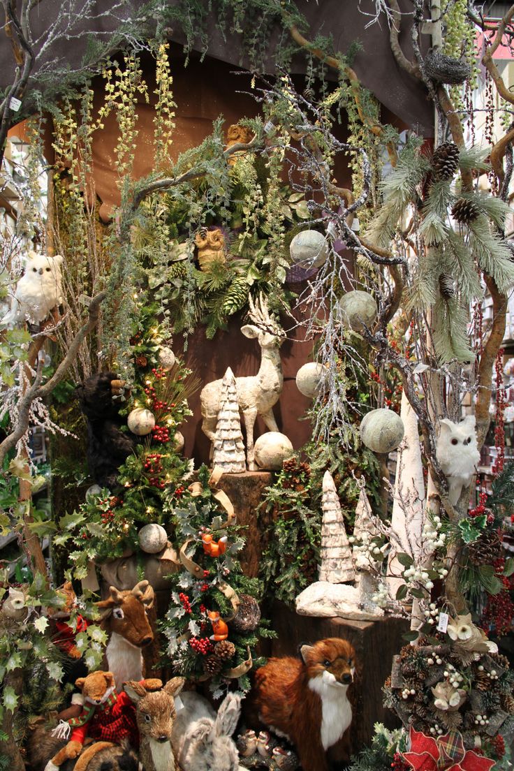 an assortment of stuffed animals and trees in a display case at a christmas market or shop