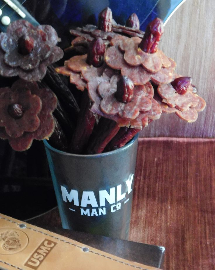 flowers in a cup sitting on a table next to a knife and some other items