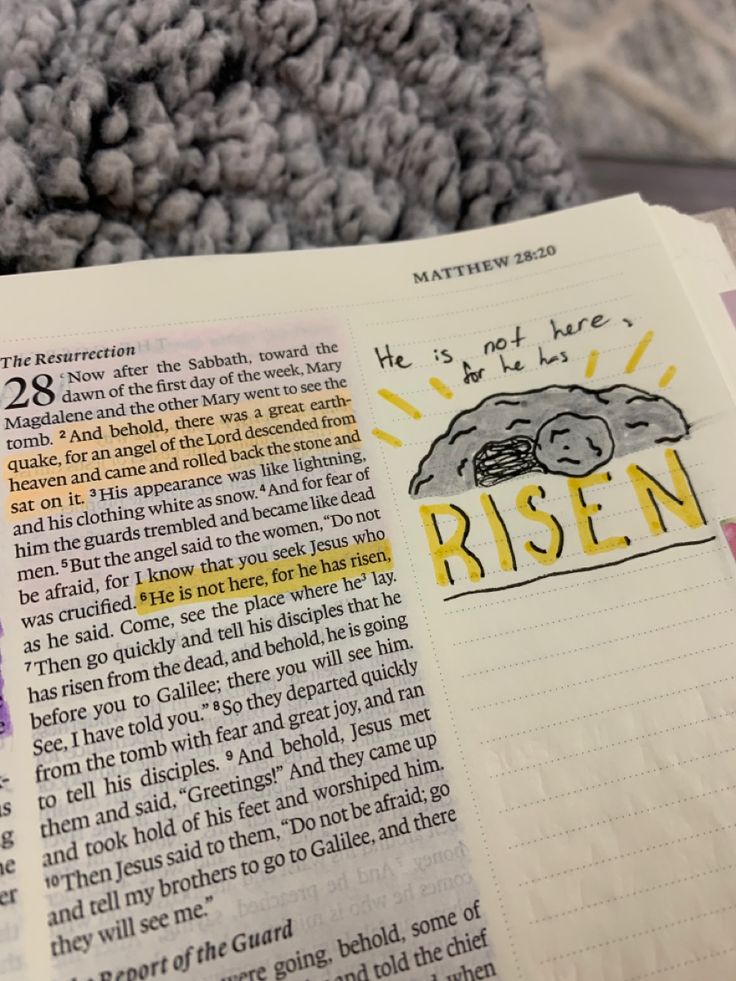 an open bible with the word risen written in yellow and purple on it, next to a pile of books