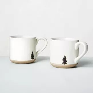 two mugs with trees painted on them sitting side by side in front of a white wall