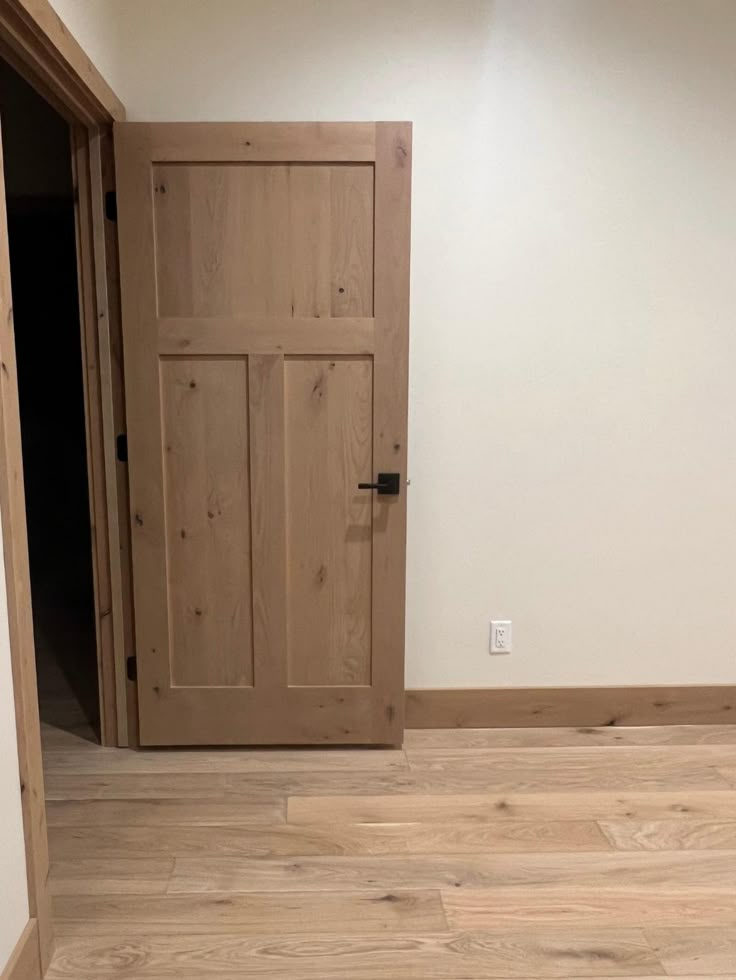 an empty room with wooden doors and hard wood flooring on the side of the wall