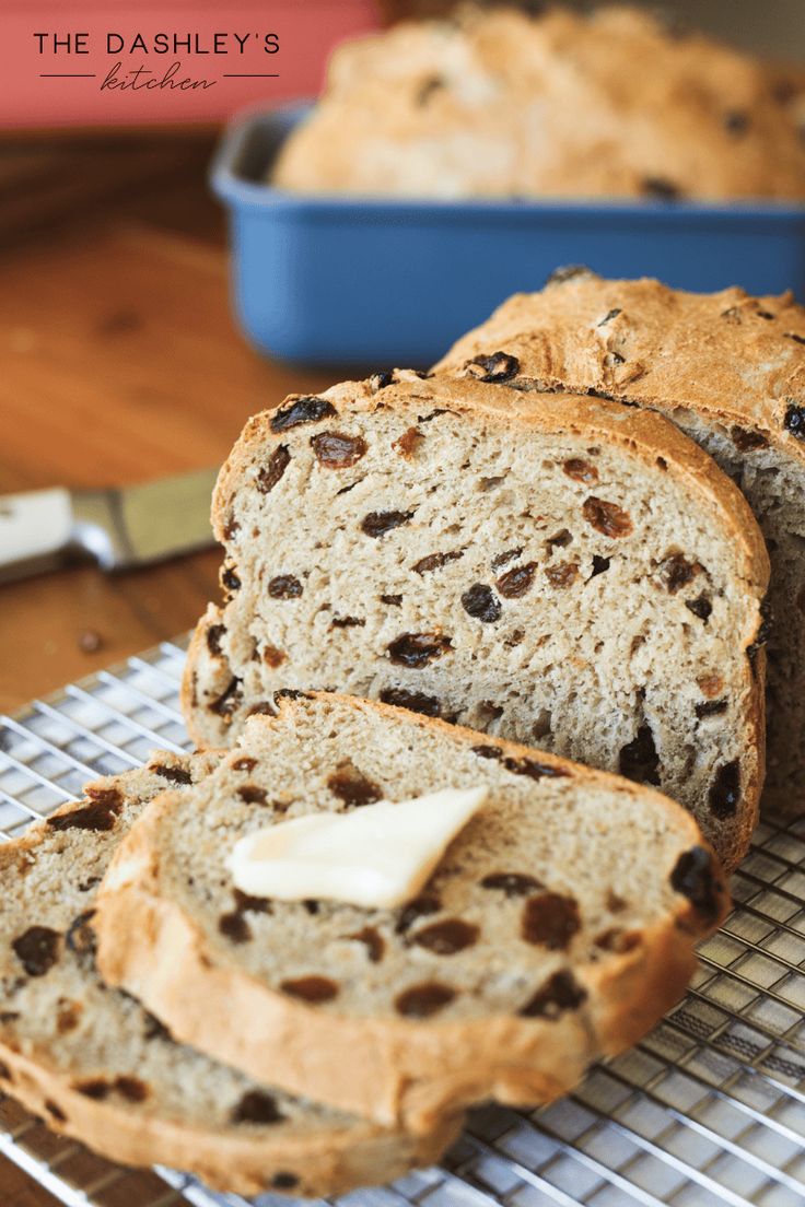 sliced loaf of bread with butter and raisins sitting on a cooling rack next to a blue dish