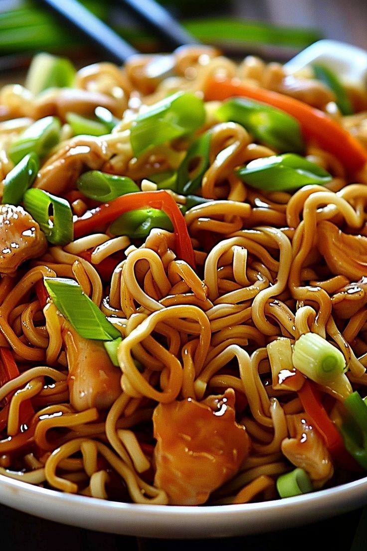 a bowl filled with noodles and vegetables next to chopsticks