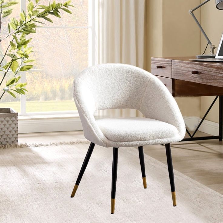 a white chair sitting on top of a wooden floor next to a desk and window