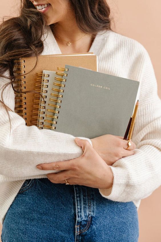 a woman holding a notebook and pen in her hands