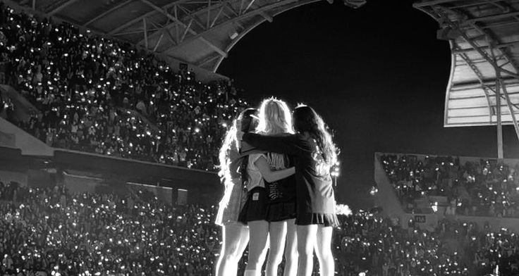 two girls standing on top of each other in front of an audience at a concert