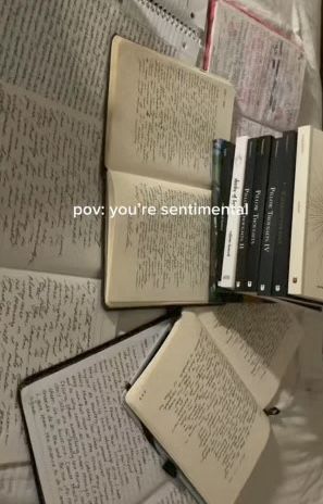 an open book sitting on top of a bed next to several other books and papers