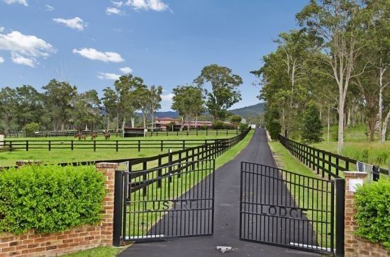 a gated driveway leading to a lush green field