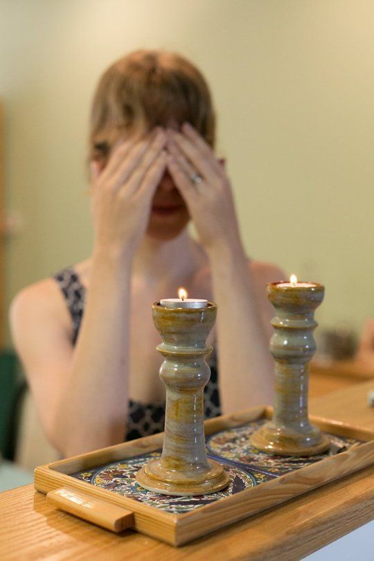 a woman covering her eyes next to two candles on a tray with a candle holder