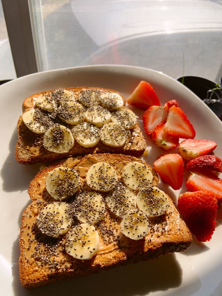 two pieces of toast with bananas and strawberries on it