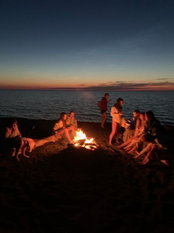 people sitting around a campfire on the beach