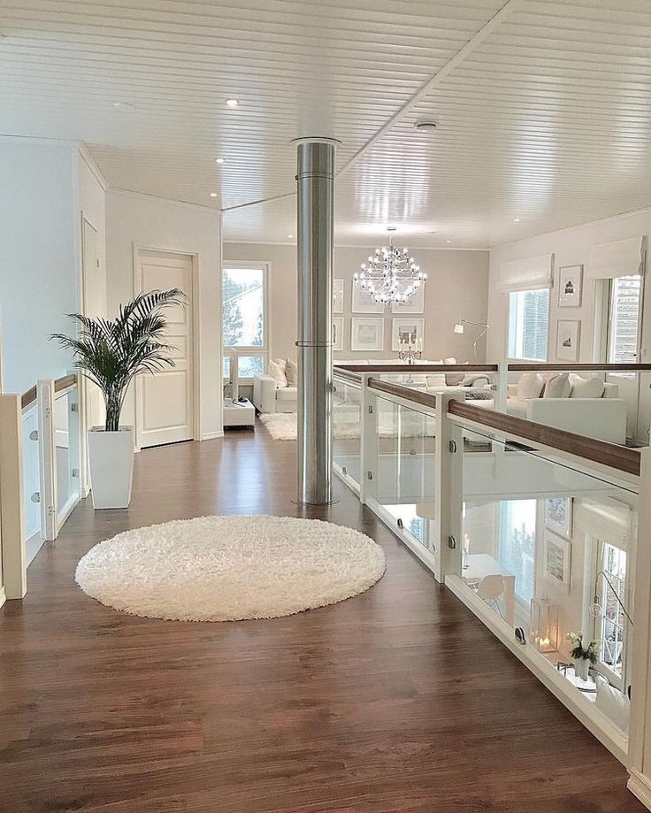 a living room filled with furniture and a white rug on top of a hard wood floor