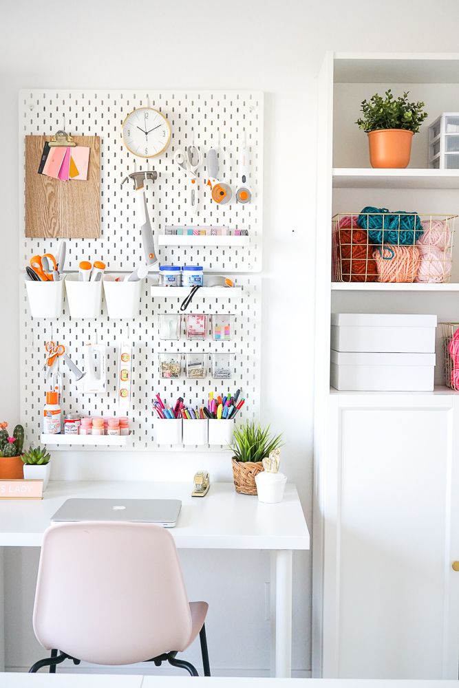 a white desk topped with a laptop computer next to a shelf filled with office supplies