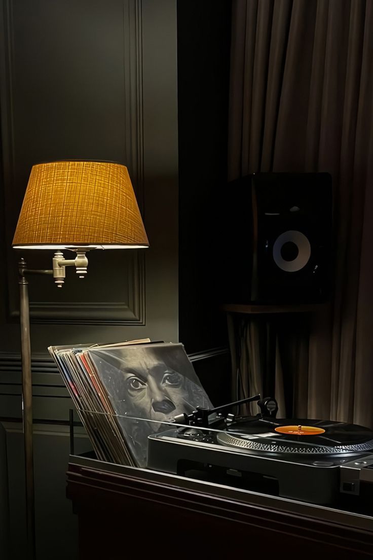 an old record player is sitting next to a lamp in a room with black walls