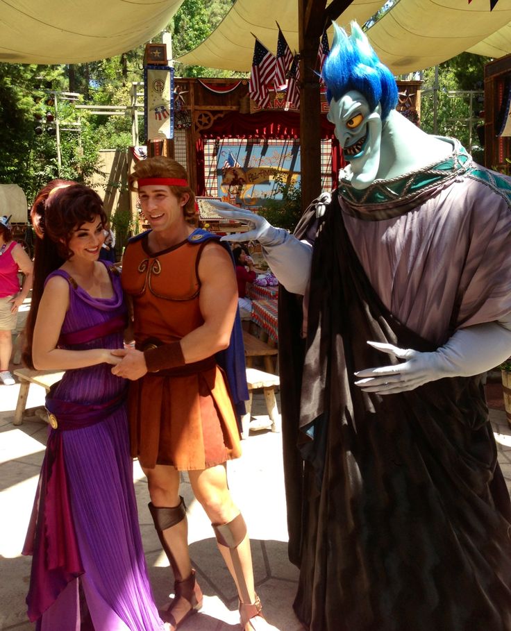 two people standing next to each other in front of a man dressed as a creature