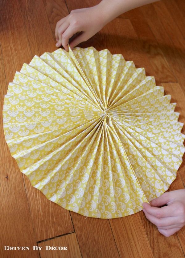 a person is holding an umbrella on the floor with their hand over it to make a paper fan