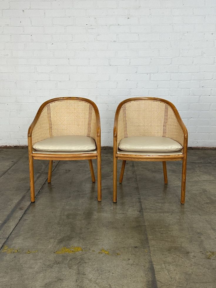 two chairs sitting next to each other in front of a white brick wall and cement floor