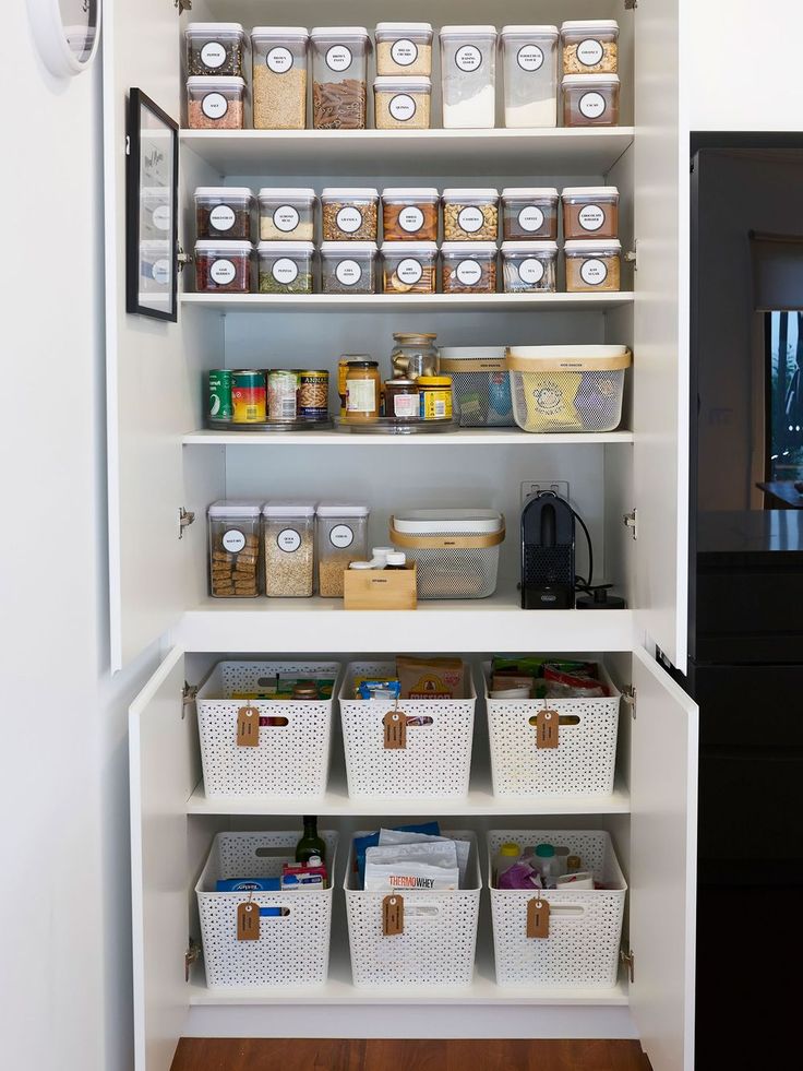 an organized pantry with white shelves and bins filled with food, drinks and other items