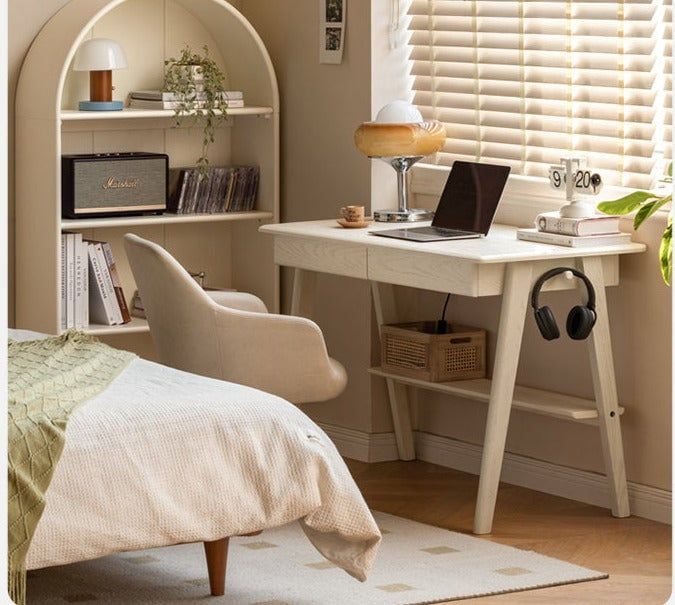 a bedroom with a bed, desk and laptop on the table in front of it