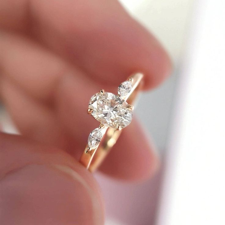 a close up of a person's hand holding a ring with two diamonds on it