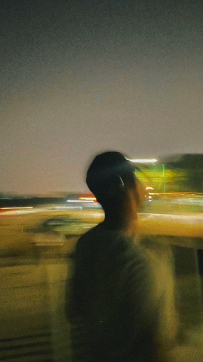 a blurry photo of a man standing in front of a building at night with his head turned to the side