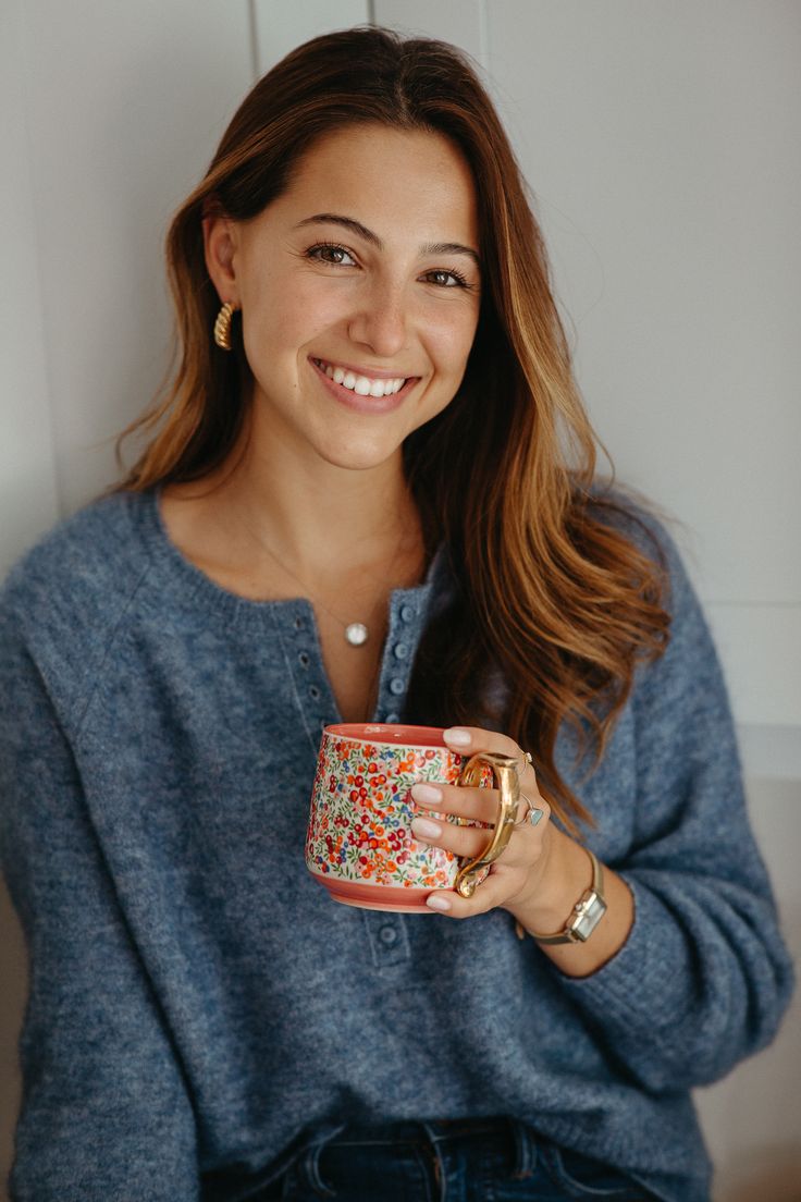 a smiling woman holding a coffee cup in her hands