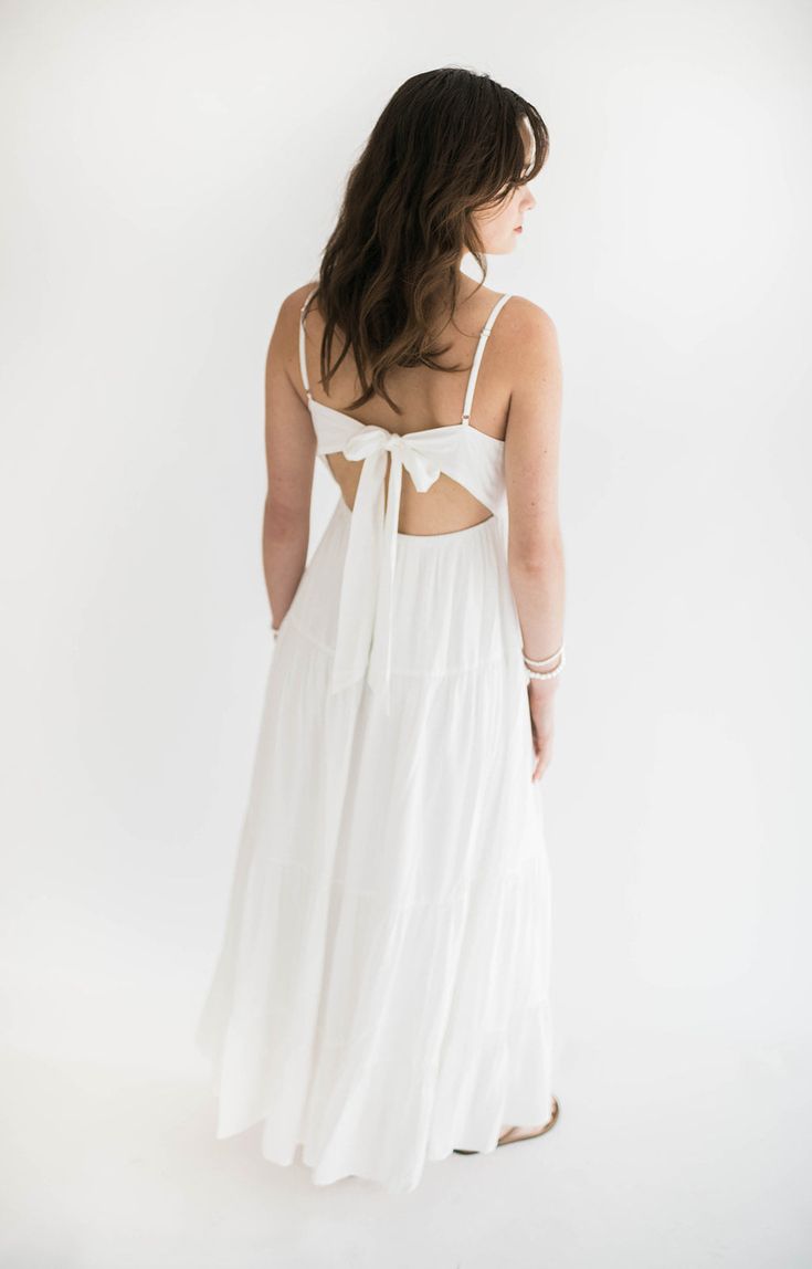 A white maxi dress is a summer must have! This stunning dress has a flowing silhouette and a classic white hue, exuding timeless charm. The open back with tie detailing adds a touch of allure and sophistication. Perfect for beach weddings, garden parties, or pretty much anything else you have going on this summer! This is a dress you will reach for over and over again. Size Chart Features: v neckline open scoop back with tie detail maxi length fully lined fabric content: 100% rayon model is wear Beachy Maxi Dress, White Beach Dress, Beach White Dress, Maxi Dress White, White Maxi Dress, Long White Dress, Dreamy Dress, Garden Parties, Denim Accessories