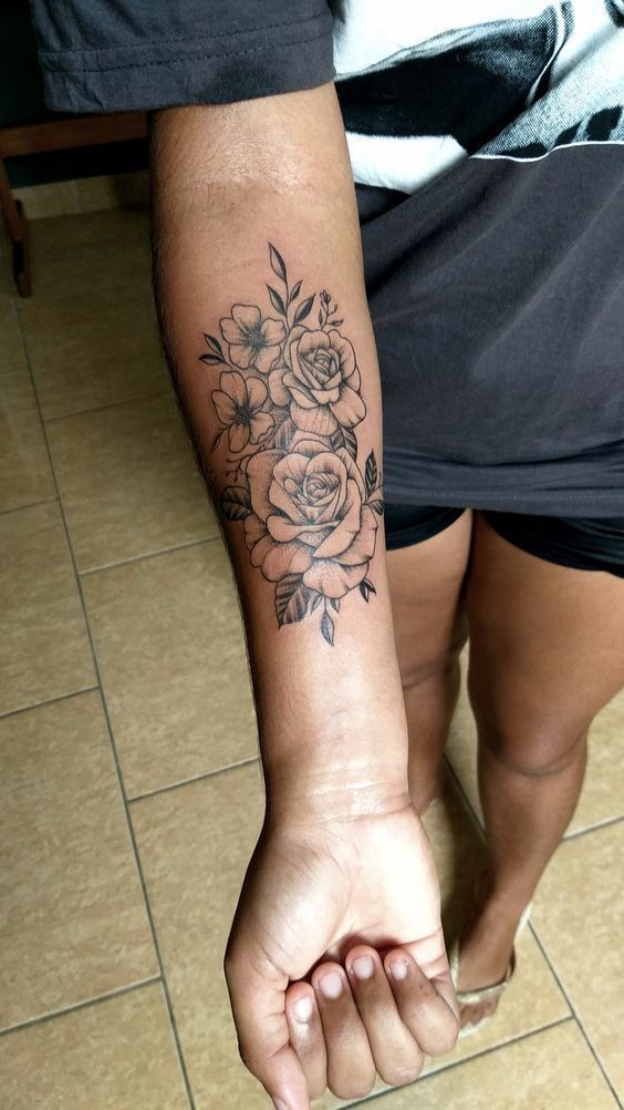 a woman with a flower tattoo on her arm and leg, sitting on the floor