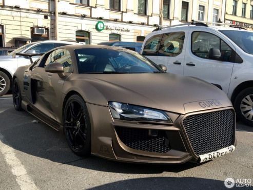 an audi sports car parked on the street in front of some other cars and people