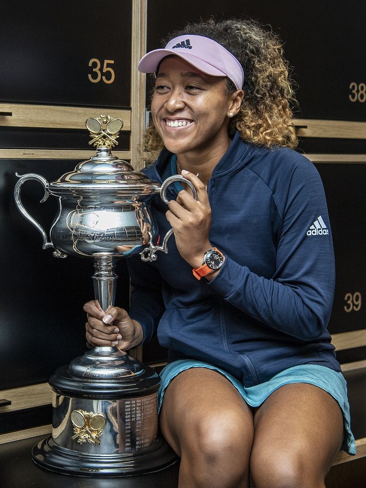 a woman holding a trophy sitting on top of a bench