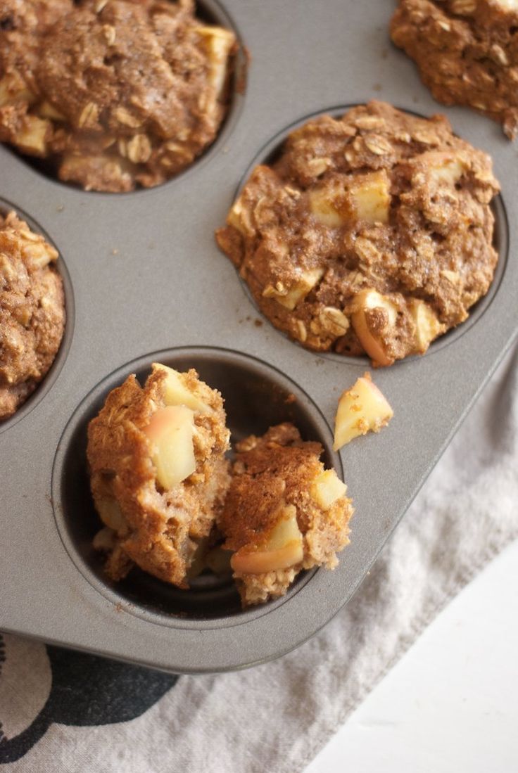 muffins in a muffin pan with apples and cinnamon crumbled on top