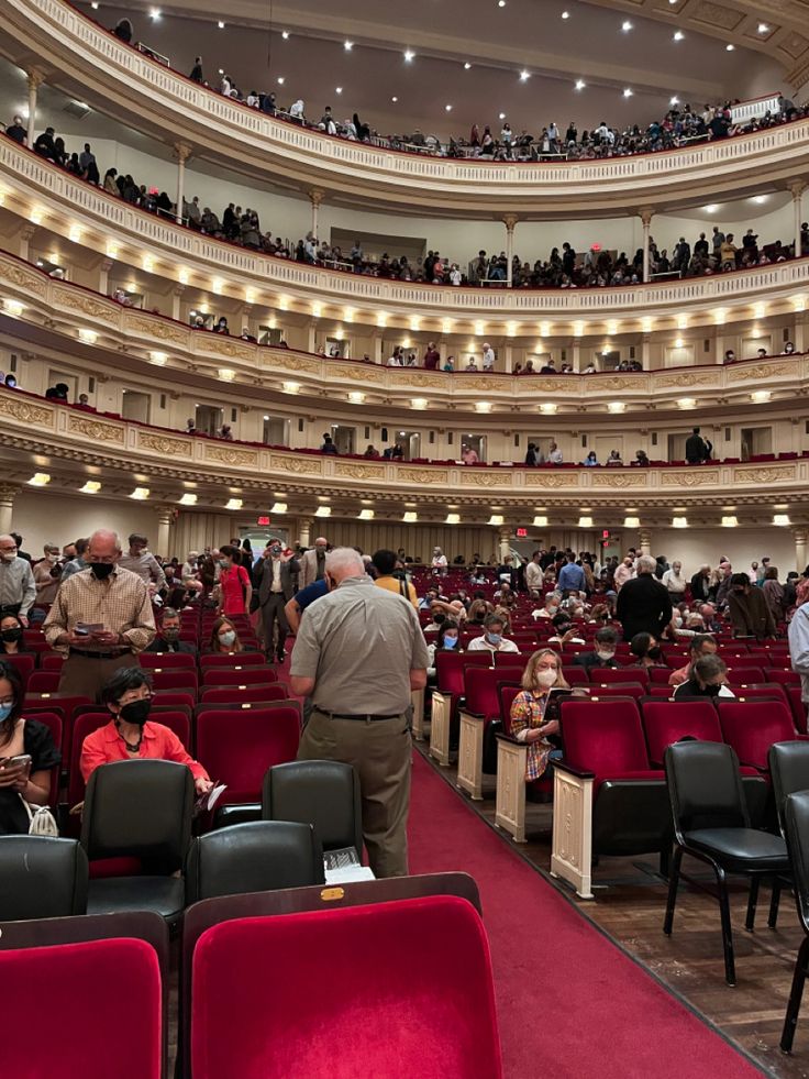 an auditorium filled with people sitting in red chairs