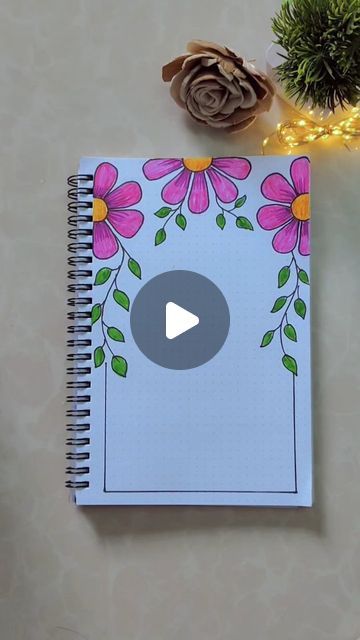 a notebook with flowers on it next to pine cones