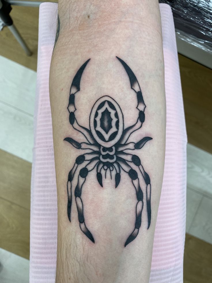 a black and white spider tattoo on the arm